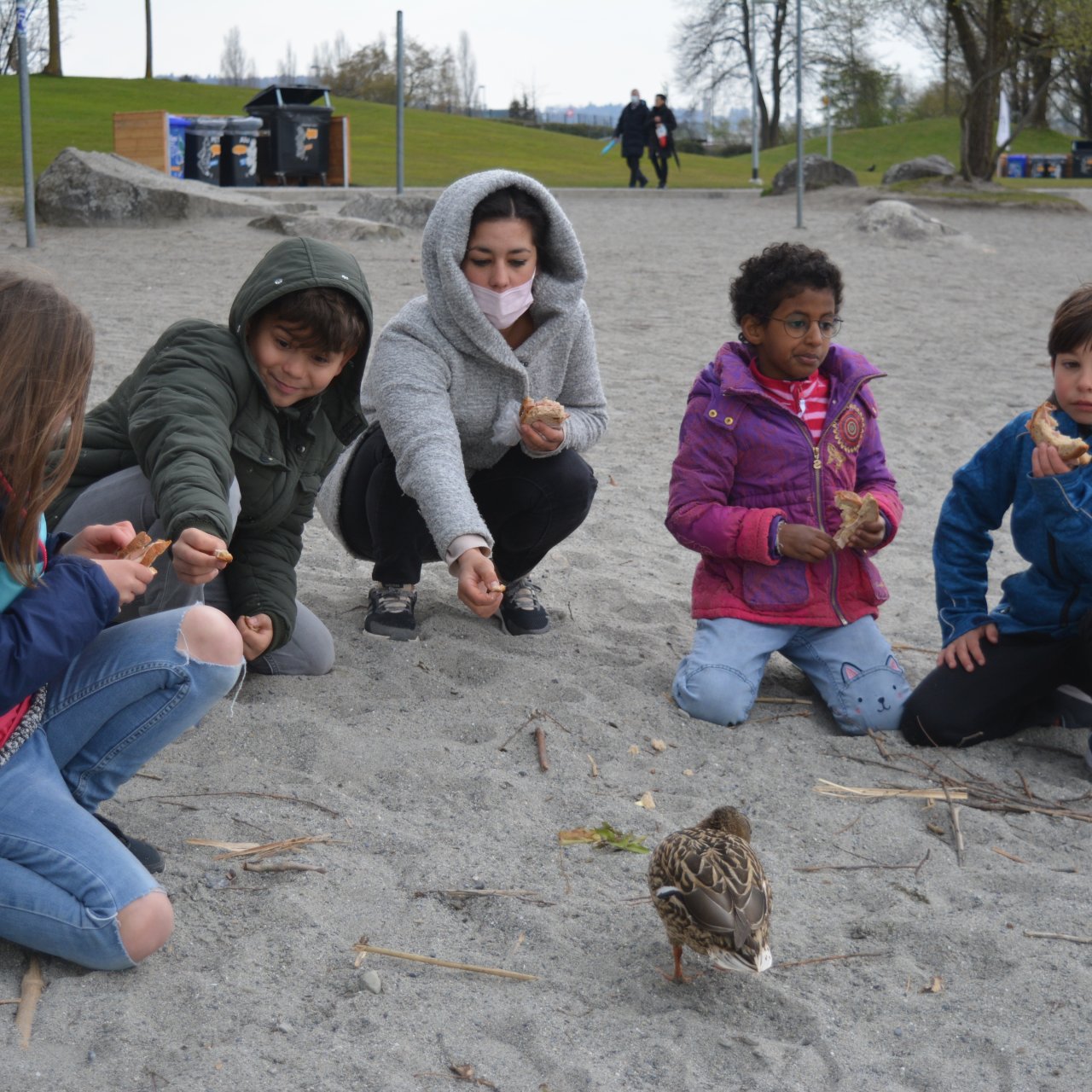 Bild Wohngruppen Gruppe mit Kindern und Jugendlichen füttert eine Ente am See.